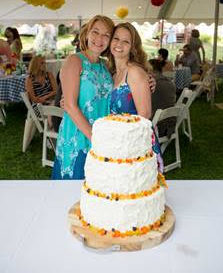 Women posing behind cake